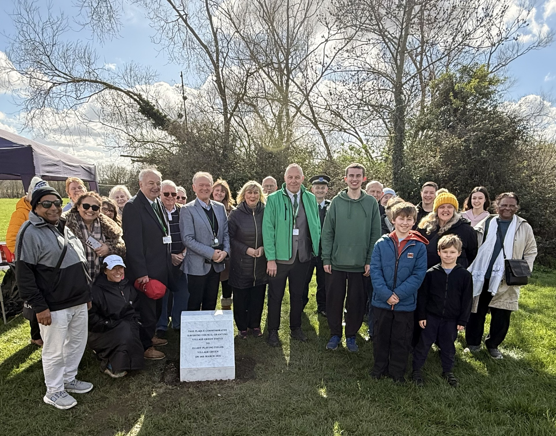 Group standing around commemorative plaque smiling