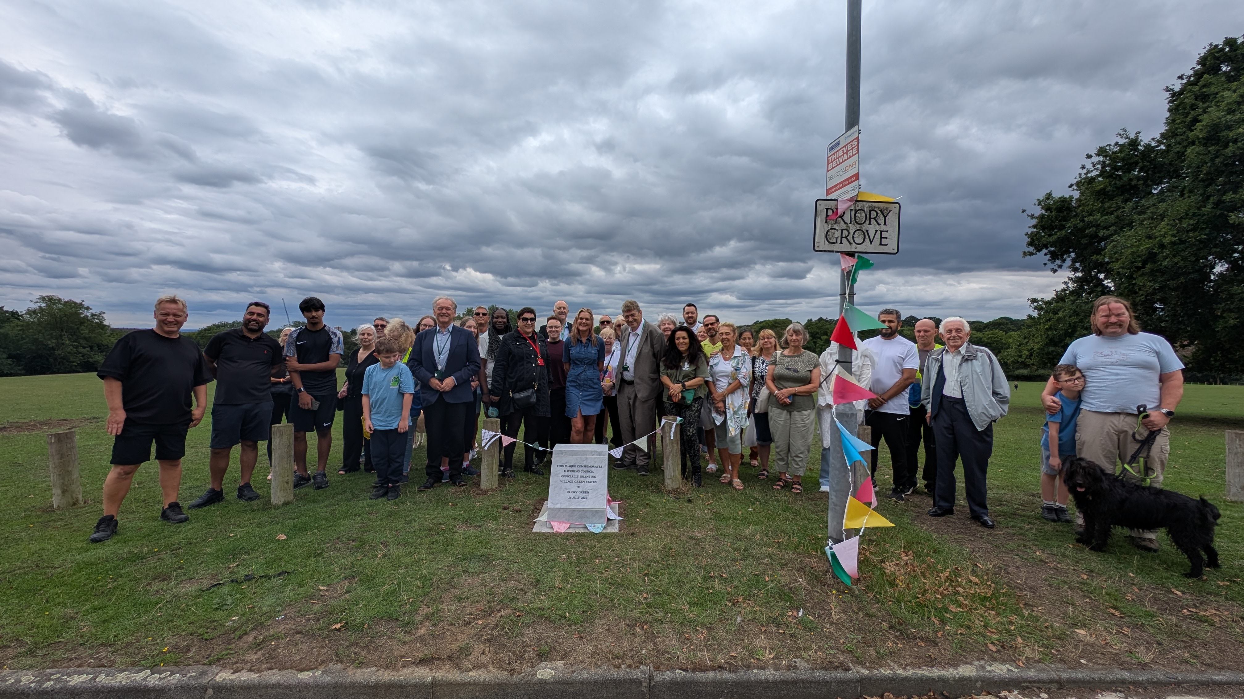 image shows group of people smiling to camera behind the white marble dedication