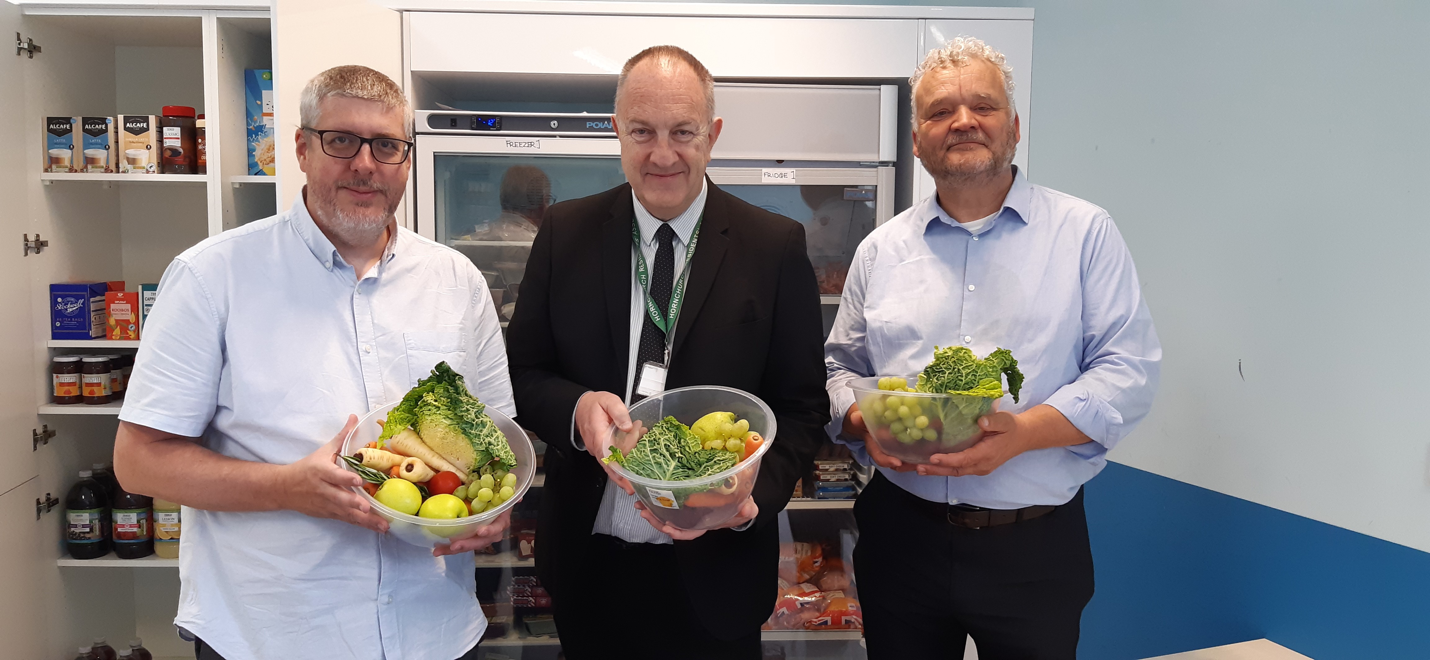 Leader of the council, Ray Morgon, in dark suit, with two men either side, all holding bowls of fresh vegetables