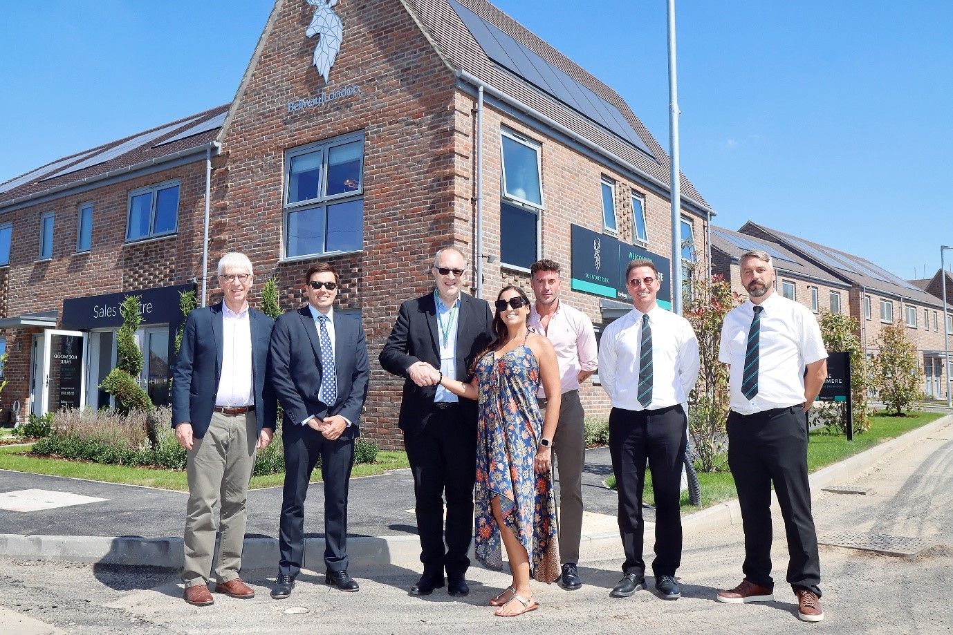 Image shows group of people smiling to camera in front of a brand new three storey town house show home
