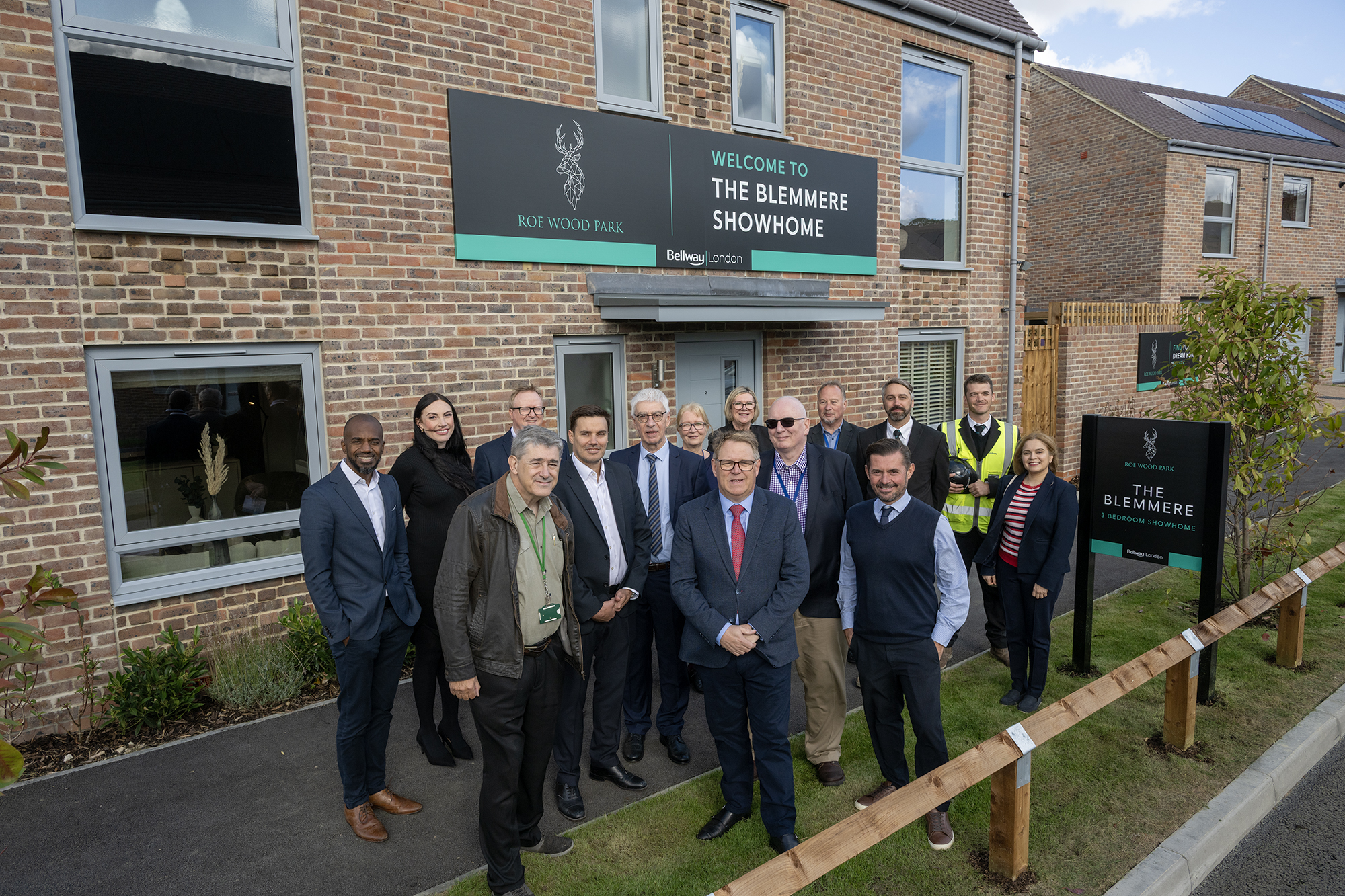 Image shows group of people smiling at camera in front of new showhome