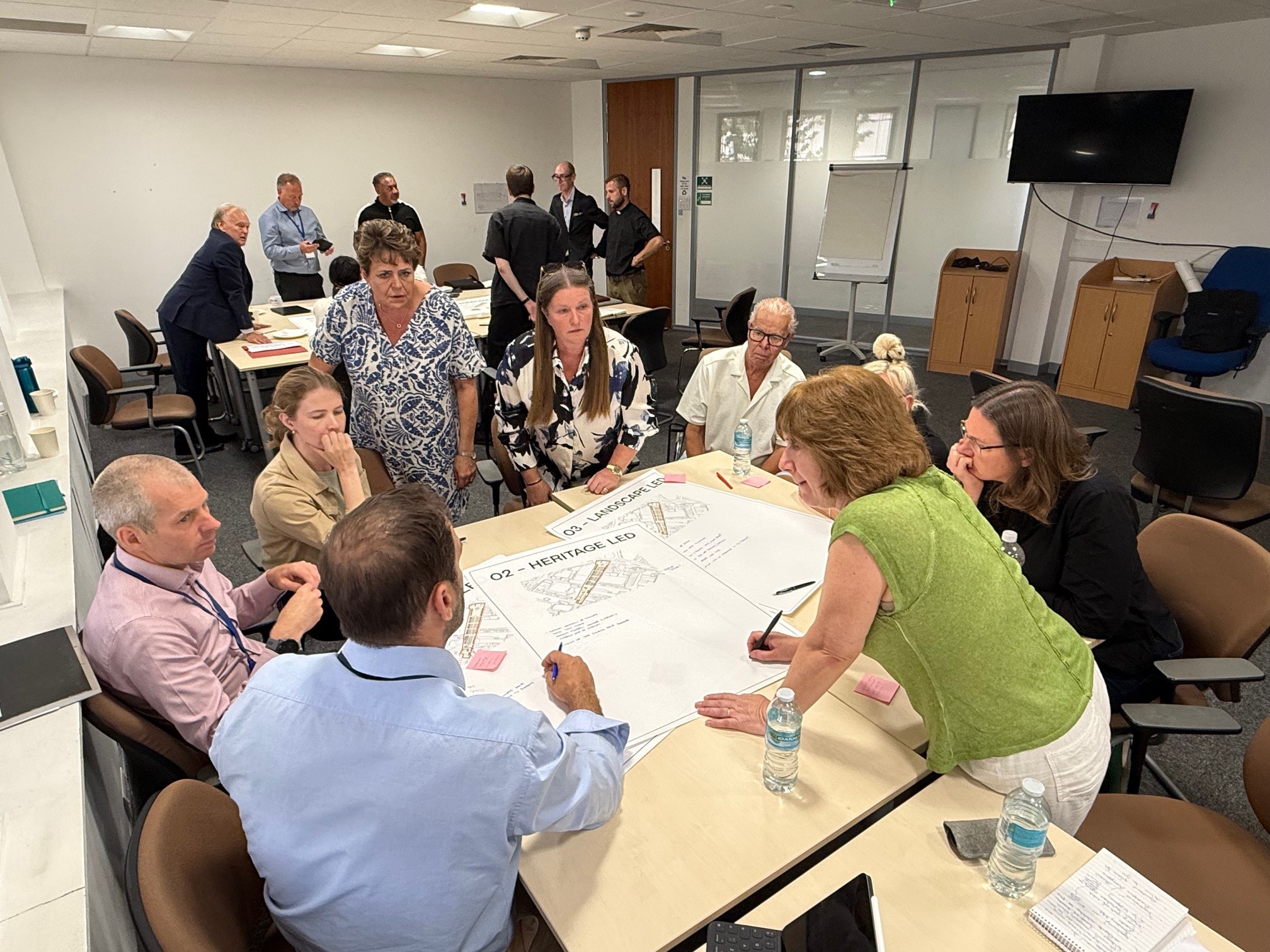 Image shows people gathered around a table working on large plans