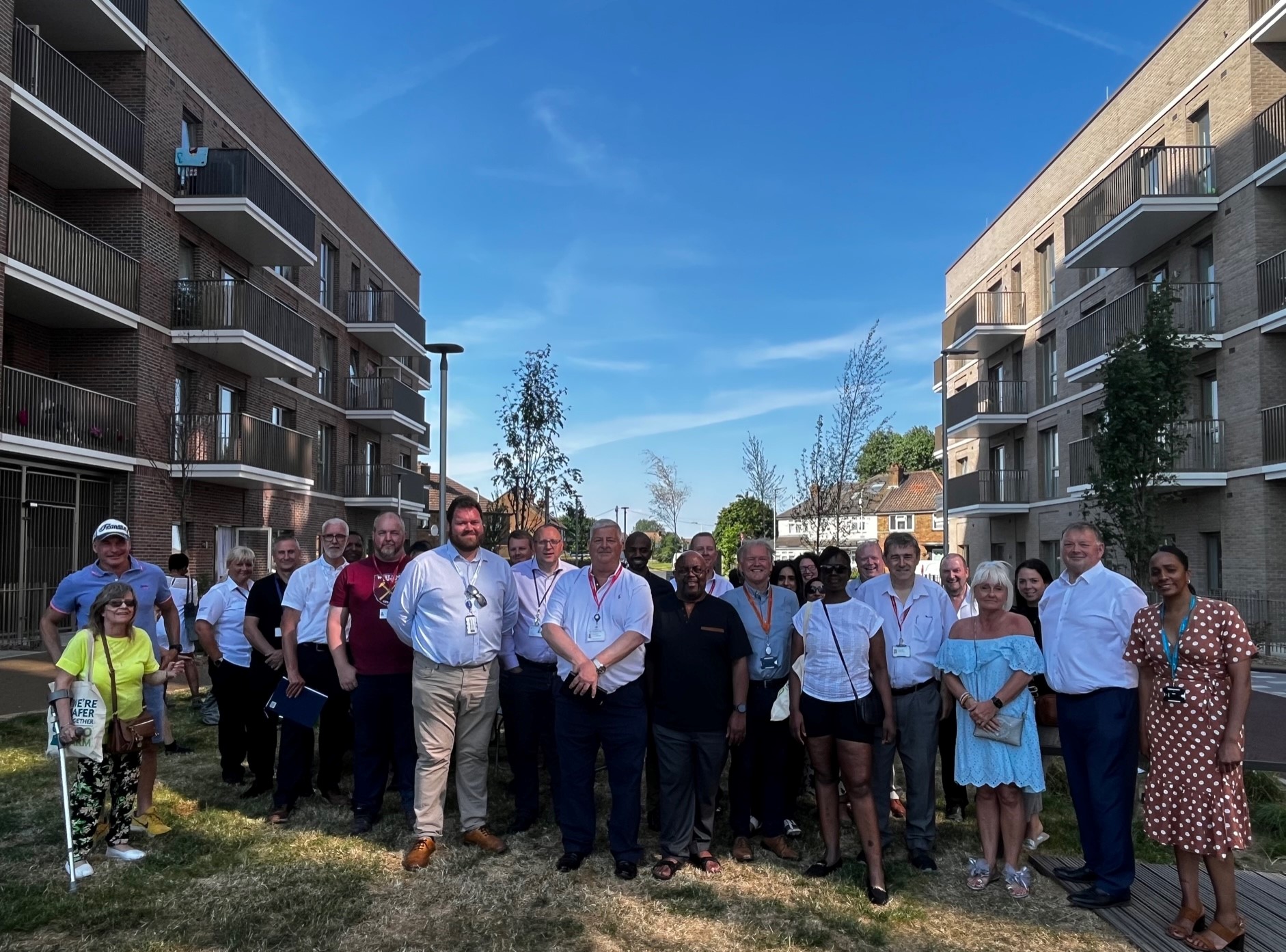 Image shows people smiling at camera between two buildings on the New Green estate